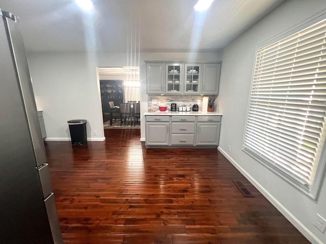 kitchen with tasteful backsplash, stainless steel refrigerator, plenty of natural light, and dark wood-type flooring