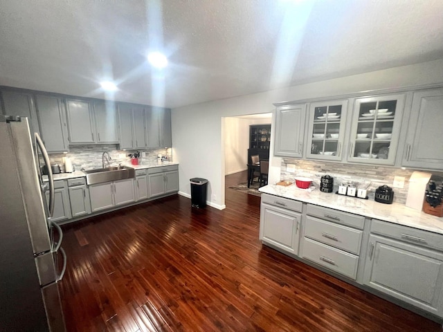 kitchen featuring stainless steel refrigerator, gray cabinetry, sink, tasteful backsplash, and dark hardwood / wood-style flooring