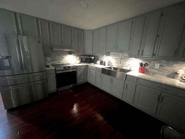 kitchen with appliances with stainless steel finishes, backsplash, dark wood-type flooring, and sink