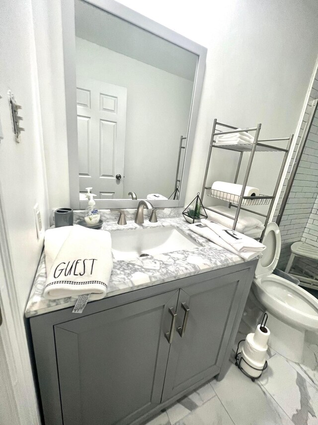 bathroom featuring tiled shower, vanity, and toilet