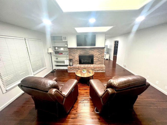 living room with dark hardwood / wood-style floors, a skylight, and a brick fireplace