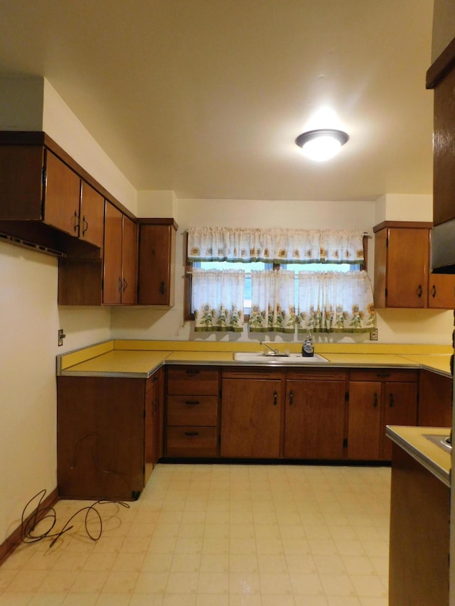 kitchen featuring brown cabinetry, light countertops, a sink, and light floors