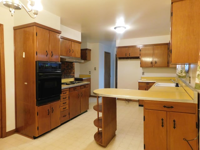 kitchen with oven, under cabinet range hood, a sink, light countertops, and light floors