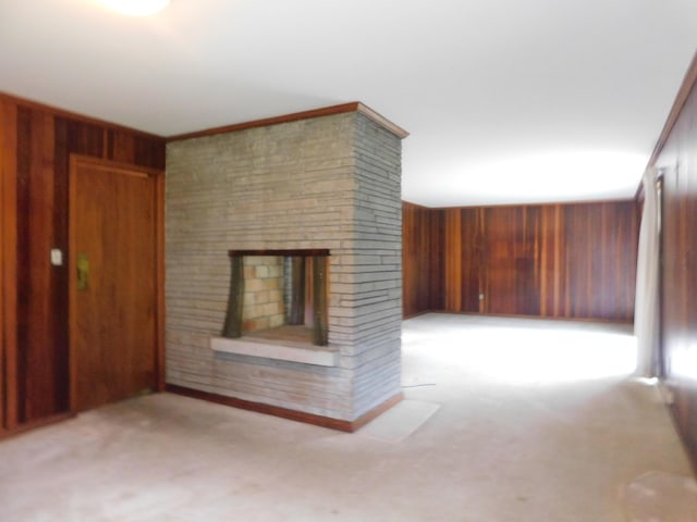 unfurnished living room with a fireplace and wood walls