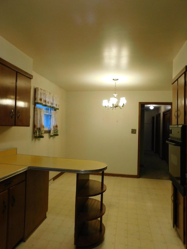 kitchen featuring light floors, baseboards, a chandelier, and oven