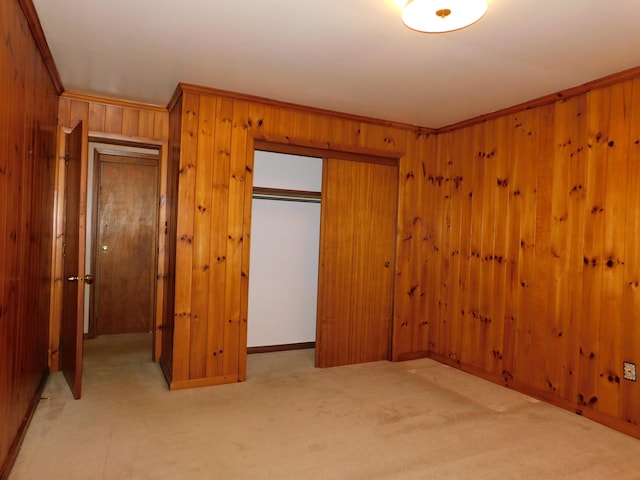 unfurnished bedroom with crown molding, a closet, carpet flooring, and wooden walls