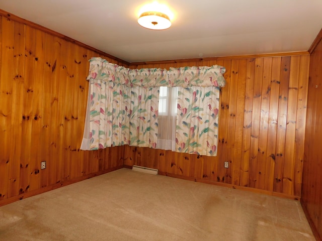 carpeted spare room with baseboards, wood walls, and baseboard heating