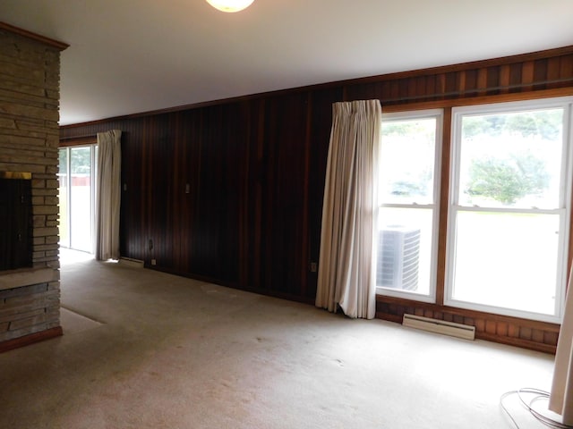 unfurnished living room with wooden walls, a fireplace, and light colored carpet