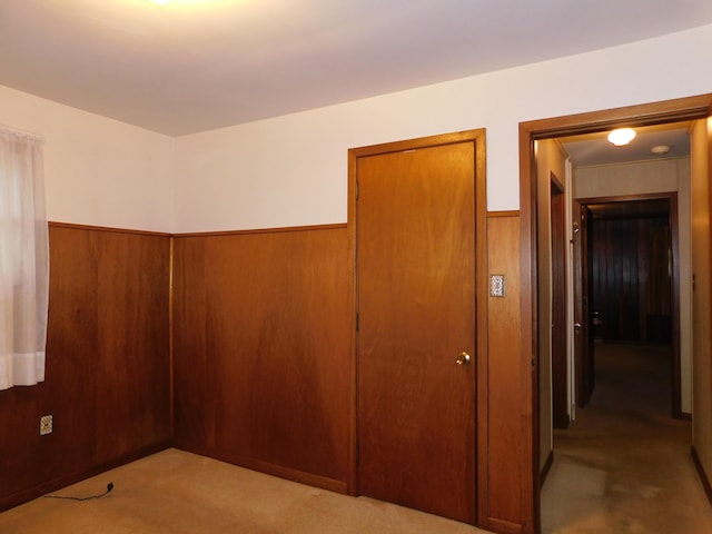 unfurnished bedroom with wood walls, a closet, and wainscoting