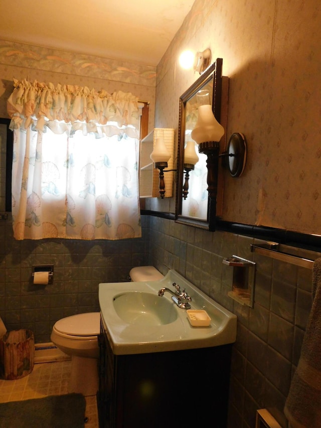 half bathroom with a wainscoted wall, tile walls, toilet, and vanity