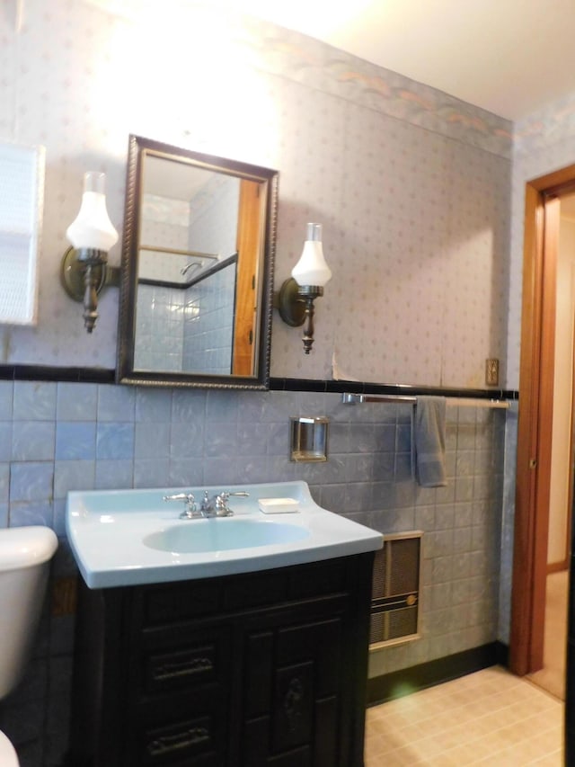 full bath featuring wallpapered walls, toilet, a wainscoted wall, walk in shower, and vanity