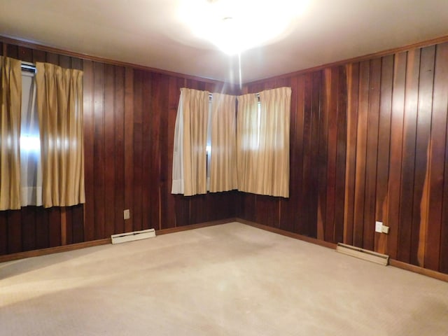 empty room featuring a baseboard radiator, wooden walls, and carpet