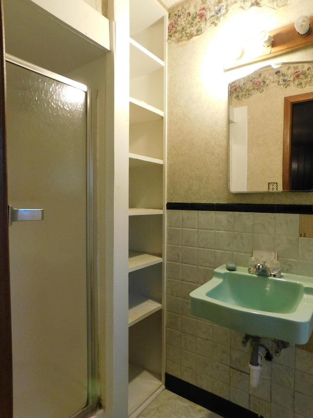 full bathroom featuring a sink, tile walls, and a shower stall