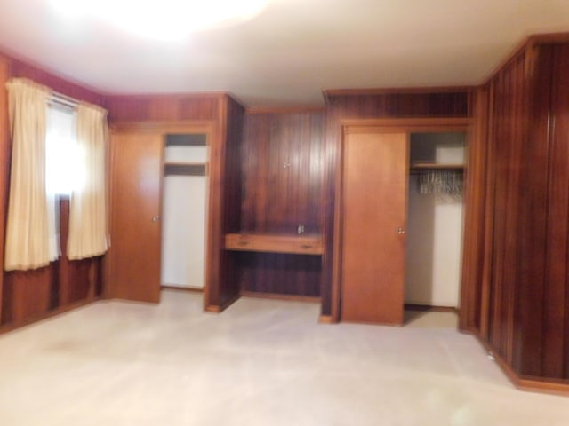 unfurnished bedroom featuring light carpet, a closet, and wooden walls