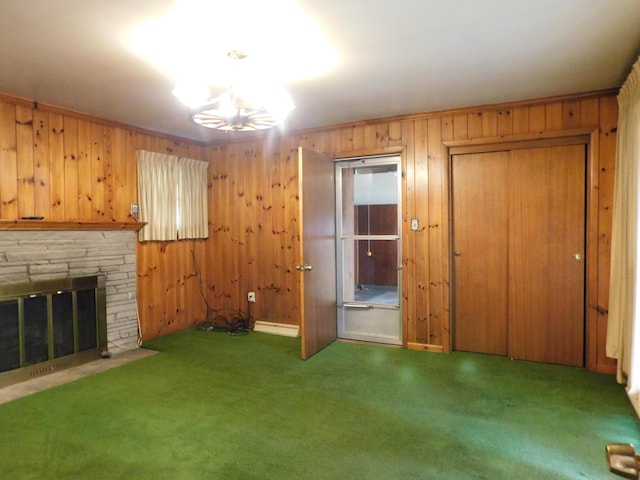 unfurnished living room featuring carpet floors, baseboard heating, wood walls, and a fireplace