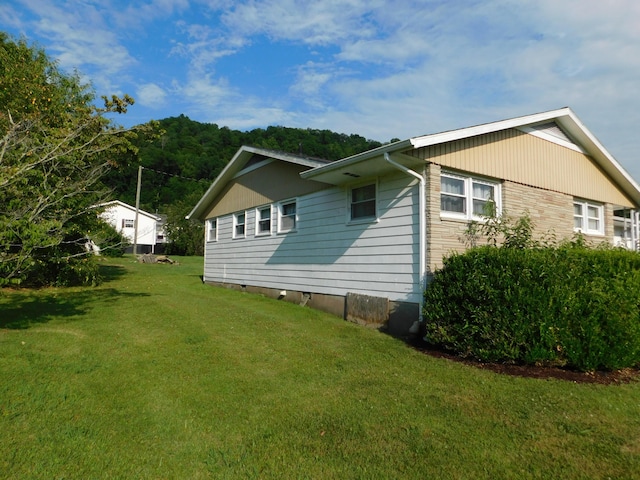 view of side of home featuring stone siding and a yard