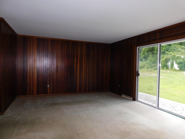 spare room featuring a baseboard heating unit, wood walls, and light colored carpet