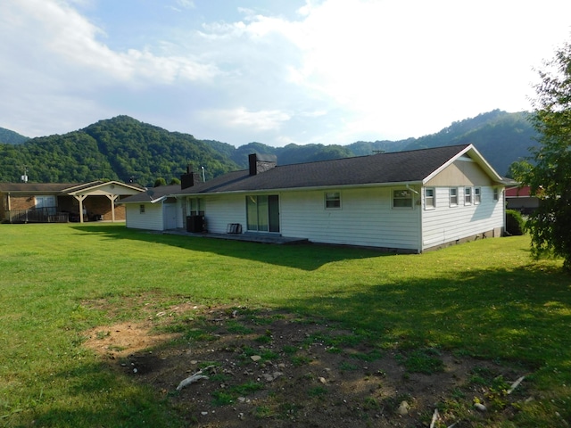 rear view of house featuring a yard, a mountain view, and a chimney