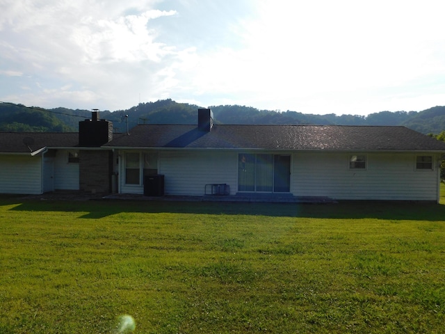 back of house featuring a lawn and a mountain view