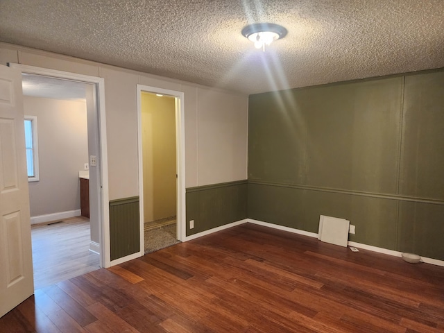 unfurnished room featuring hardwood / wood-style flooring and a textured ceiling