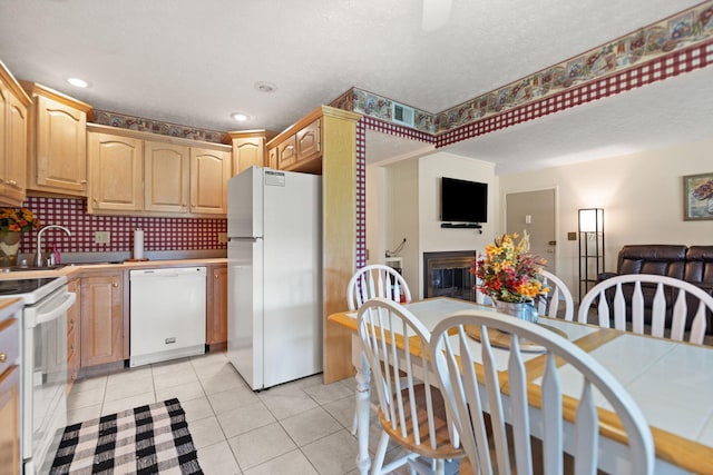 kitchen featuring white appliances, light tile patterned floors, a textured ceiling, decorative backsplash, and sink