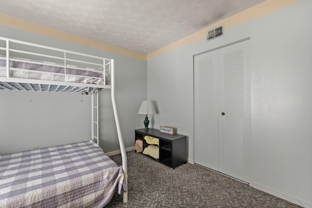 bedroom featuring a closet, dark colored carpet, and a textured ceiling