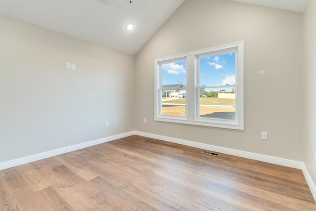 spare room featuring light wood-type flooring and vaulted ceiling