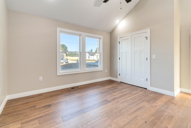 unfurnished bedroom with hardwood / wood-style floors, high vaulted ceiling, a closet, and ceiling fan