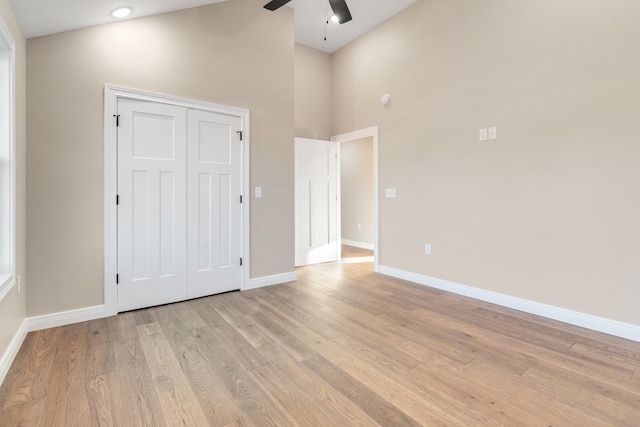 unfurnished bedroom with a closet, light hardwood / wood-style flooring, high vaulted ceiling, and ceiling fan