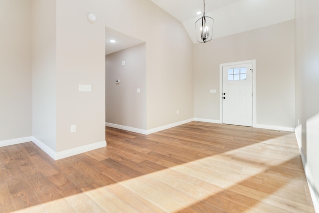 foyer with lofted ceiling, an inviting chandelier, and light wood-type flooring