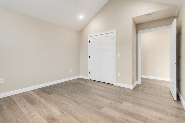 unfurnished bedroom featuring a closet, light hardwood / wood-style floors, and high vaulted ceiling