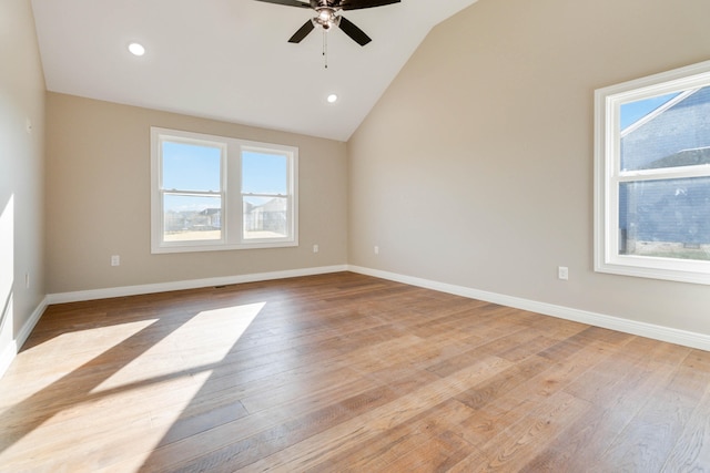 spare room featuring lofted ceiling, light wood-type flooring, and a wealth of natural light