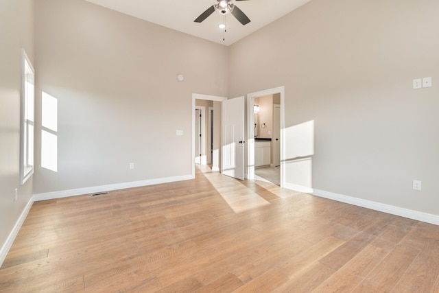 empty room featuring ceiling fan, high vaulted ceiling, and light hardwood / wood-style flooring