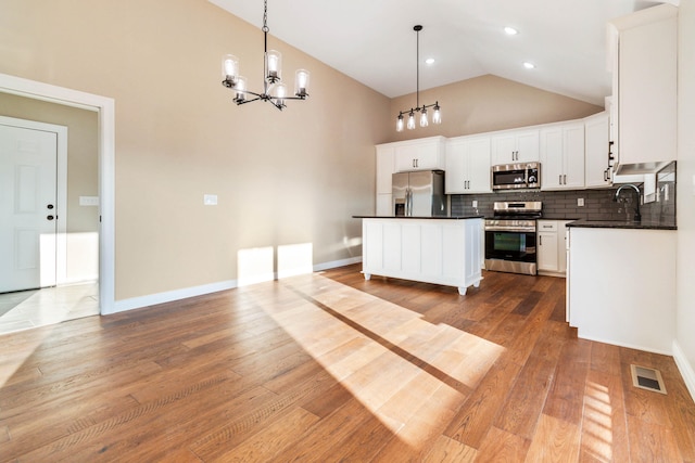 kitchen with appliances with stainless steel finishes, white cabinets, light wood-type flooring, and a kitchen island