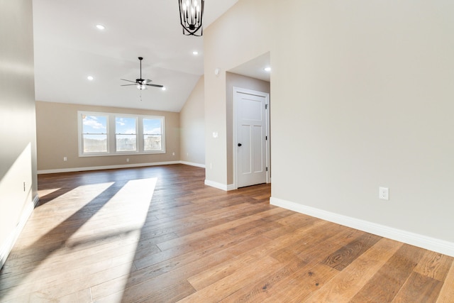 unfurnished living room with light hardwood / wood-style floors, high vaulted ceiling, and ceiling fan with notable chandelier