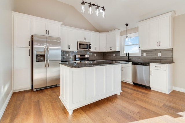 kitchen with appliances with stainless steel finishes, decorative light fixtures, light hardwood / wood-style floors, and white cabinetry