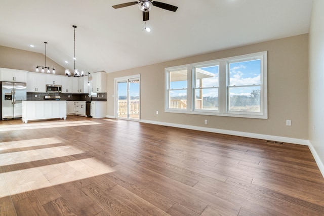 unfurnished living room with lofted ceiling, light hardwood / wood-style flooring, and ceiling fan with notable chandelier