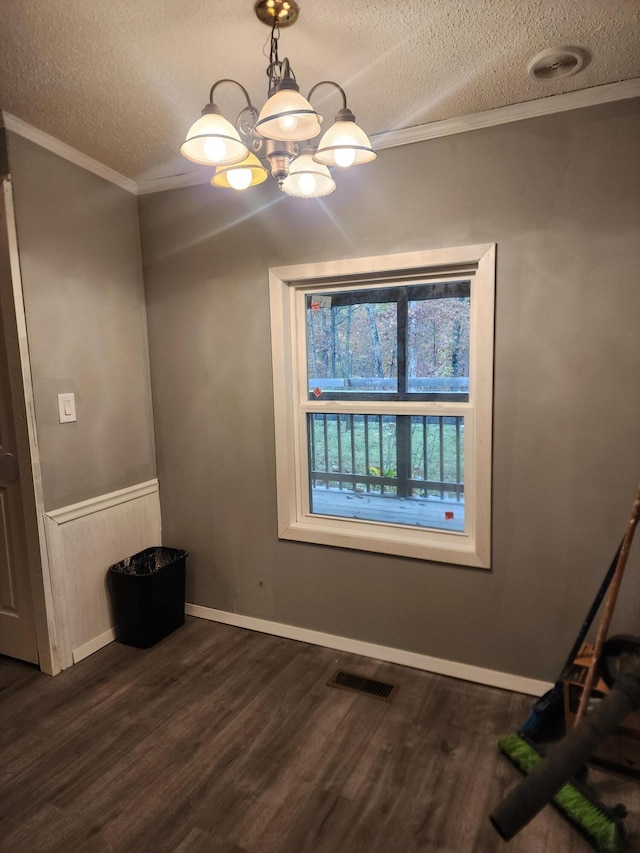 spare room featuring a notable chandelier, dark hardwood / wood-style floors, crown molding, and a textured ceiling