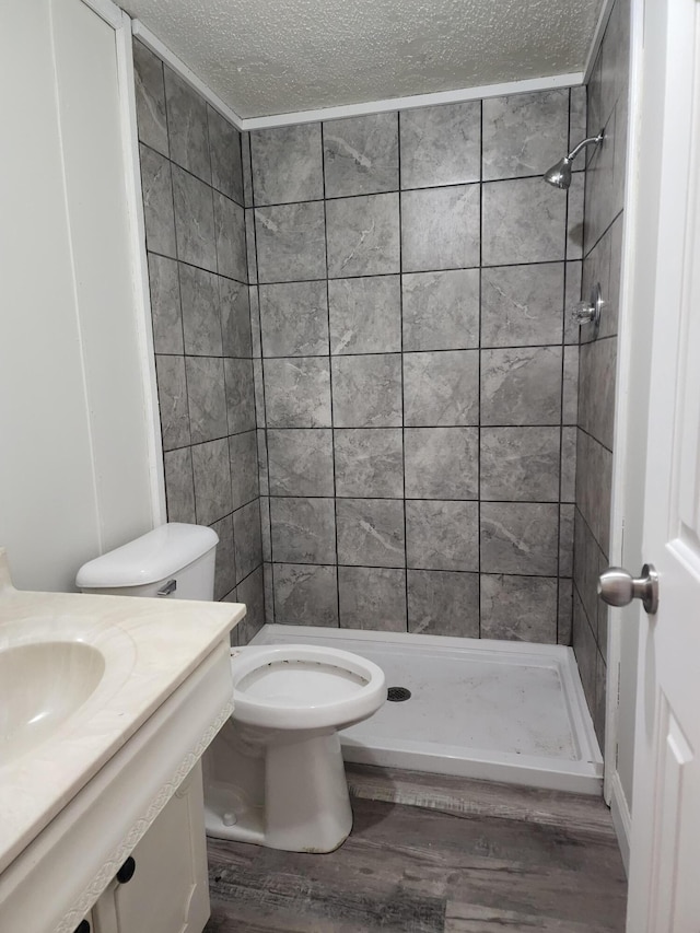 bathroom with a tile shower, a textured ceiling, sink, wood-type flooring, and toilet