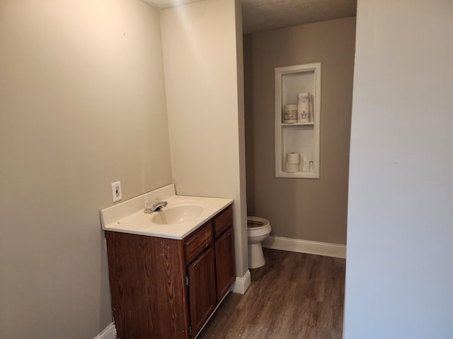 bathroom with hardwood / wood-style floors, vanity, and toilet