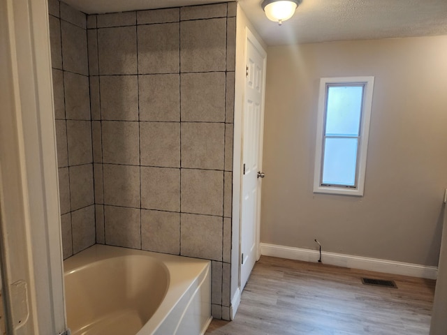 bathroom featuring wood-type flooring and a textured ceiling