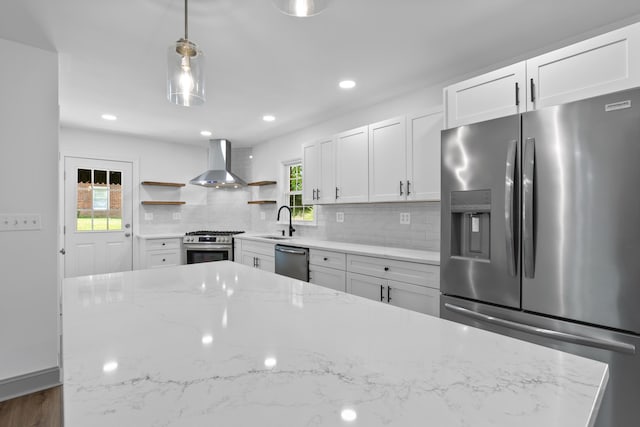 kitchen featuring white cabinets, hanging light fixtures, wall chimney exhaust hood, and stainless steel appliances