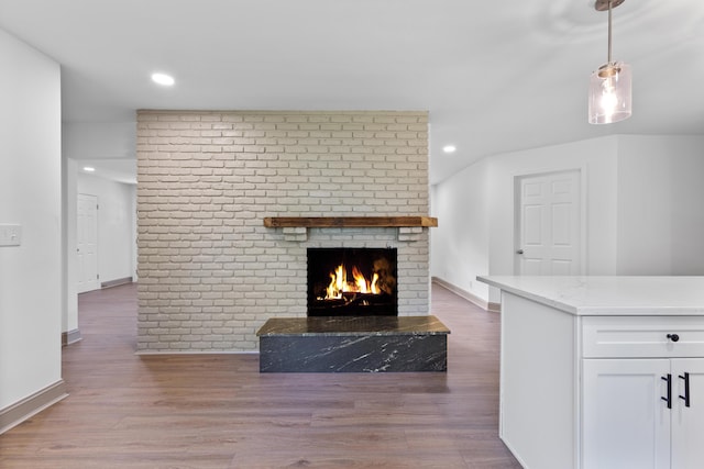 unfurnished living room with hardwood / wood-style flooring and a brick fireplace