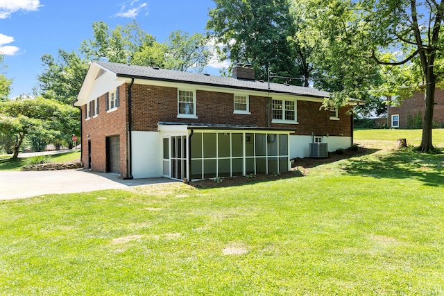 rear view of house with a garage, a yard, and central AC