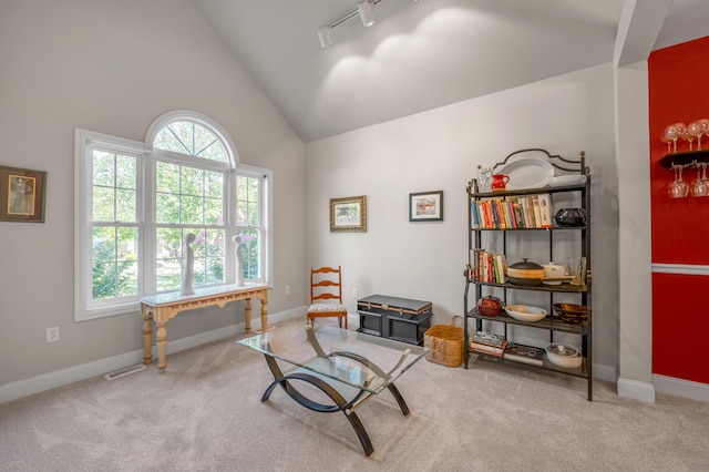 living area with carpet flooring, high vaulted ceiling, and track lighting