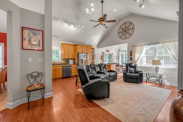 living room featuring light wood-type flooring, high vaulted ceiling, ceiling fan, and sink