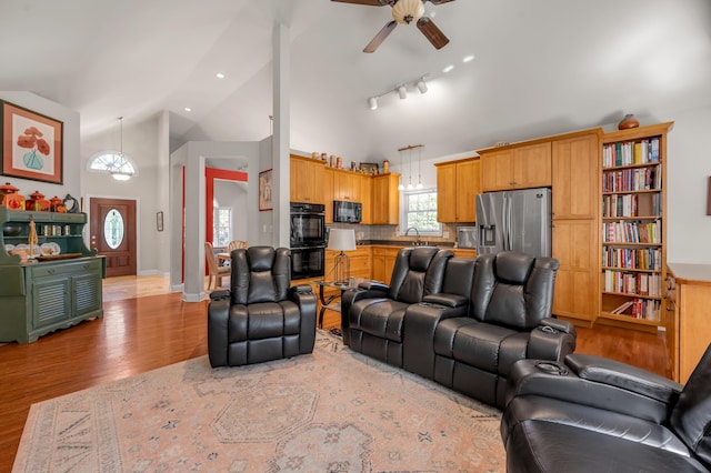 living room with ceiling fan, light wood-type flooring, high vaulted ceiling, and track lighting