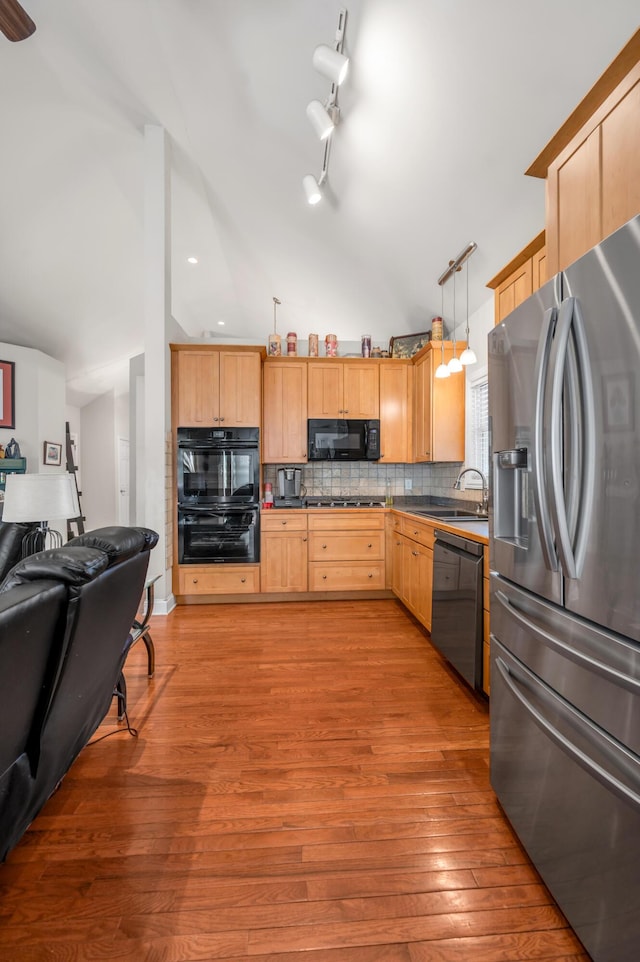 kitchen featuring black appliances, pendant lighting, light wood-type flooring, and light brown cabinets