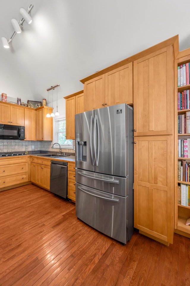 kitchen featuring decorative backsplash, stainless steel appliances, sink, decorative light fixtures, and hardwood / wood-style floors