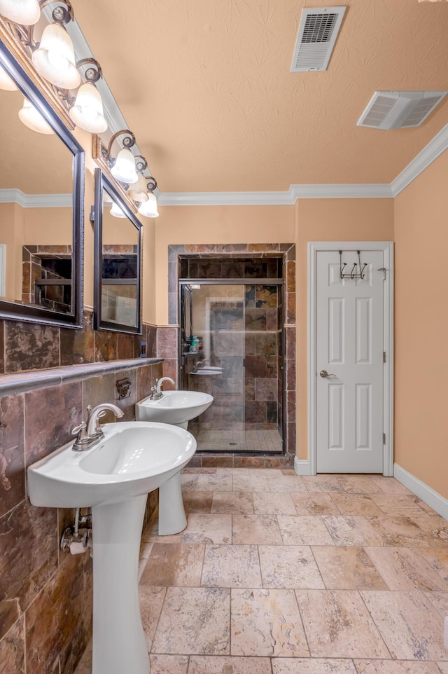 bathroom with crown molding, double sink, and an enclosed shower